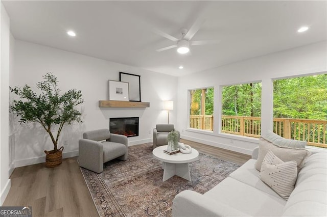 living room featuring ceiling fan, a glass covered fireplace, baseboards, wood finished floors, and recessed lighting