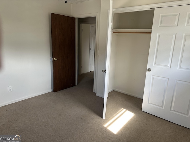 unfurnished bedroom with carpet, a closet, and baseboards