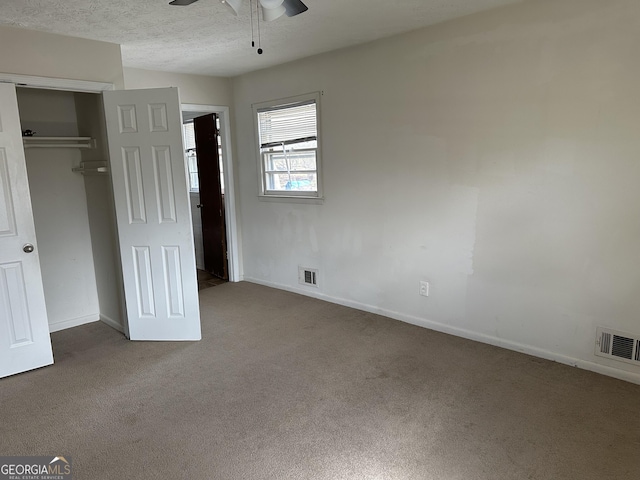 unfurnished bedroom with carpet floors, a closet, baseboards, a ceiling fan, and a textured ceiling