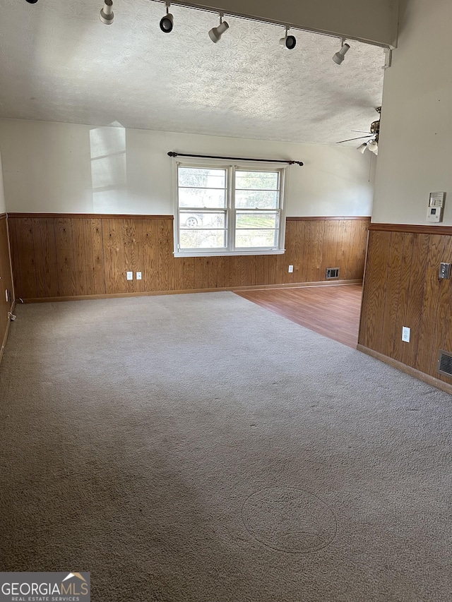 2195 Wilson Rd NW, Conyers, GA 30012 - carpeted spare room with a wainscoted wall, wood walls, a ceiling fan, a textured ceiling, and rail lighting