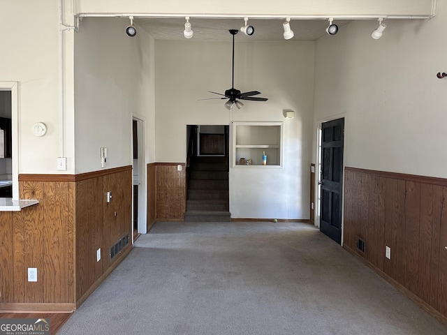 2195 Wilson Rd NW, Conyers, GA 30012 - unfurnished living room featuring track lighting, a towering ceiling, a wainscoted wall, a ceiling fan, and wood walls