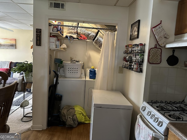 laundry room with washing machine and clothes dryer and wood finished floors