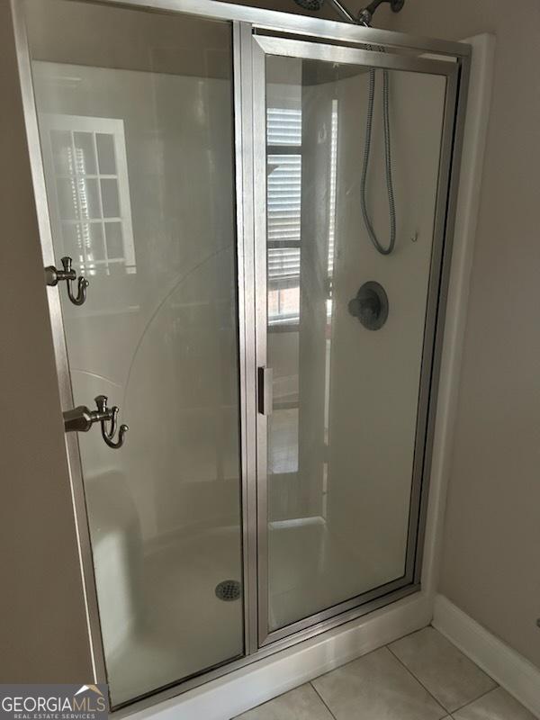 bathroom featuring tile patterned floors, a stall shower, and baseboards