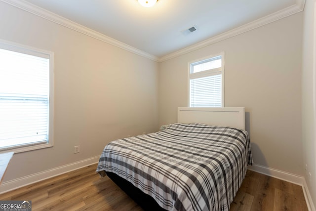 bedroom with ornamental molding, baseboards, and wood finished floors