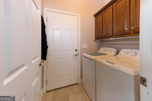 laundry area featuring washing machine and clothes dryer, cabinet space, and light tile patterned floors