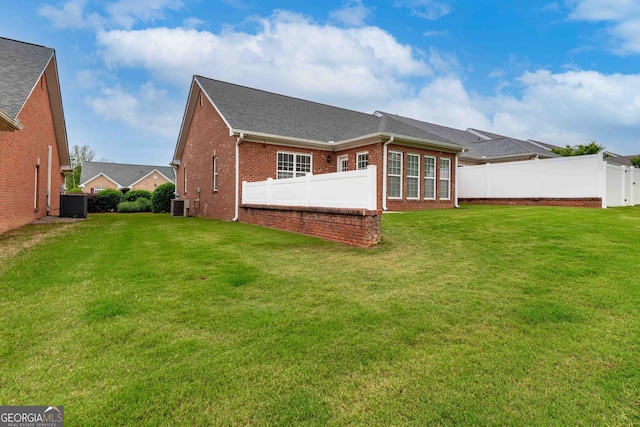 back of house with central air condition unit, brick siding, and a shingled roof