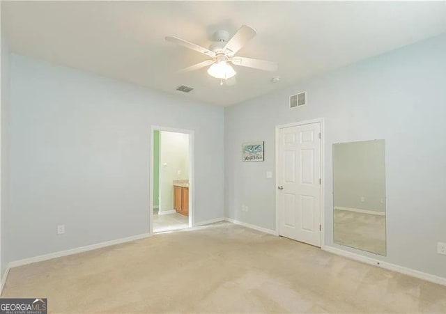 spare room with ceiling fan, light colored carpet, and baseboards