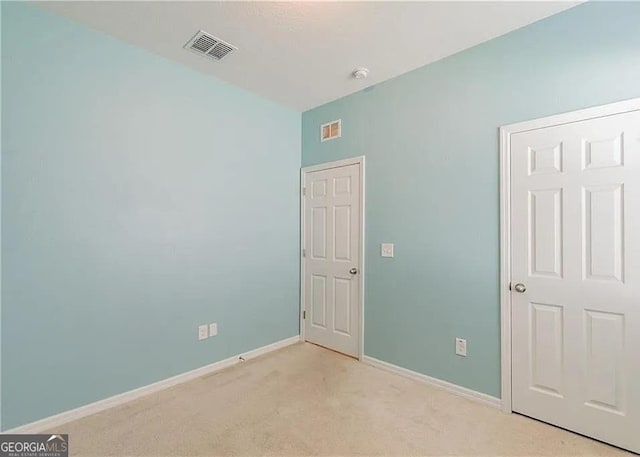 spare room featuring light colored carpet and baseboards