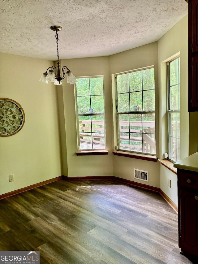 305 Glenloch Ln, Stockbridge, GA 30281 - unfurnished dining area with a chandelier, dark wood finished floors, baseboards, and a textured ceiling