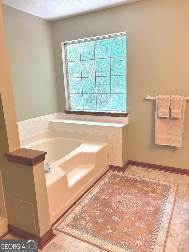 305 Glenloch Ln, Stockbridge, GA 30281 - bathroom featuring a garden tub, baseboards, and a textured ceiling