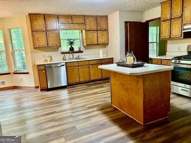 305 Glenloch Ln, Stockbridge, GA 30281 - kitchen with stainless steel appliances, brown cabinetry, light countertops, wood finished floors, and a textured ceiling