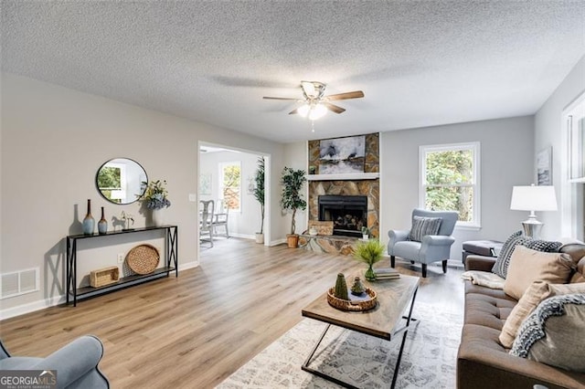 10213 Tall Pine Ct, Villa Rica, GA 30180 - living room featuring ceiling fan, light wood-style floors, a textured ceiling, a fireplace, and baseboards