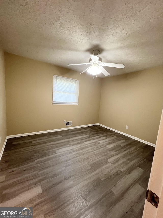 spare room with a ceiling fan, baseboards, a textured ceiling, and dark wood-style flooring