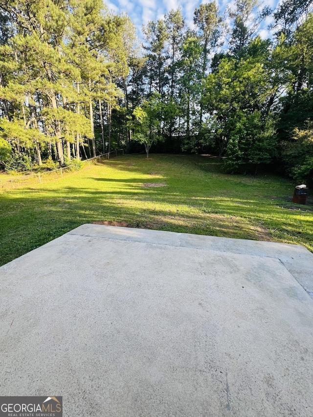 view of grassy yard with a patio area and view of scattered trees