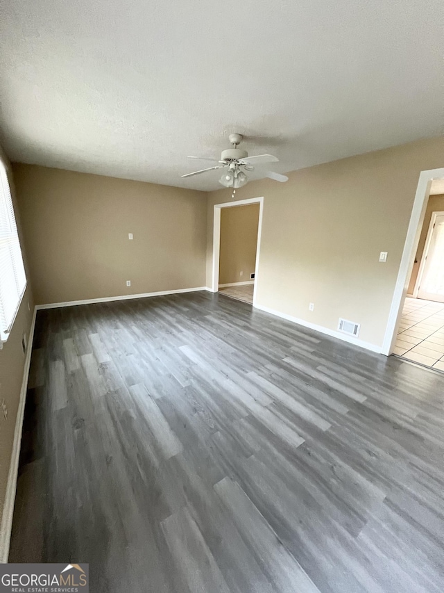 unfurnished room featuring ceiling fan, wood finished floors, and baseboards