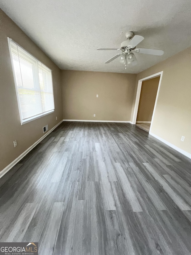 empty room with ceiling fan, dark wood-style flooring, baseboards, and a textured ceiling