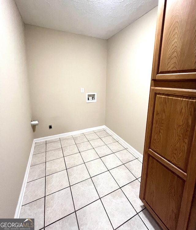 laundry room featuring washer hookup, light tile patterned floors, baseboards, and a textured ceiling