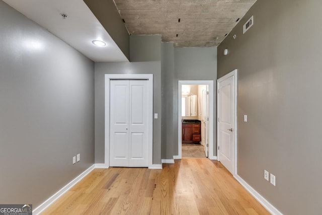 890 Memorial Dr SE Unit 105, Atlanta, GA 30316 - unfurnished bedroom with light wood-type flooring, baseboards, ensuite bathroom, and a closet