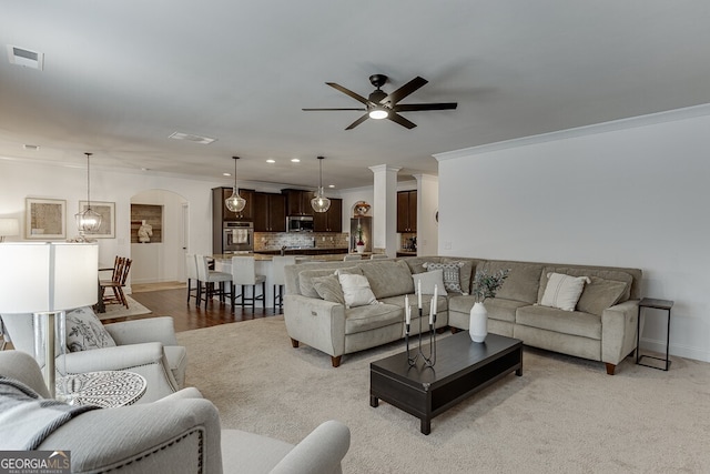 living room featuring ceiling fan, arched walkways, ornamental molding, baseboards, and recessed lighting