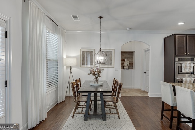 dining area with dark wood-type flooring, arched walkways, a chandelier, baseboards, and recessed lighting