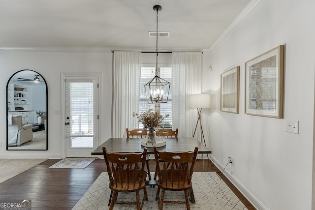 dining space with ornamental molding, a chandelier, dark wood finished floors, and baseboards