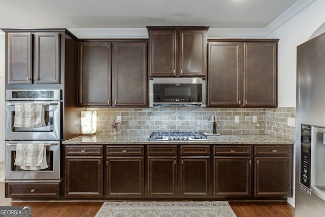 kitchen featuring stainless steel appliances, dark wood finished floors, light stone counters, dark brown cabinetry, and crown molding
