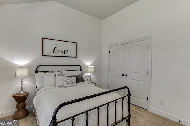 bedroom with light carpet, baseboards, a closet, and vaulted ceiling