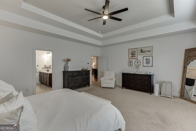 bedroom featuring a tray ceiling, ensuite bath, and carpet flooring