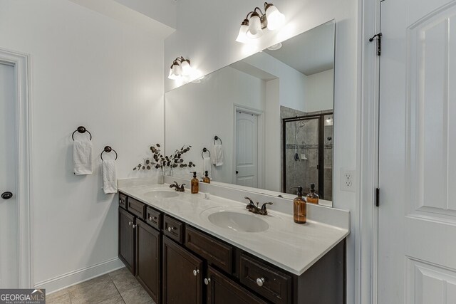 bathroom featuring a stall shower, double vanity, baseboards, and tile patterned flooring