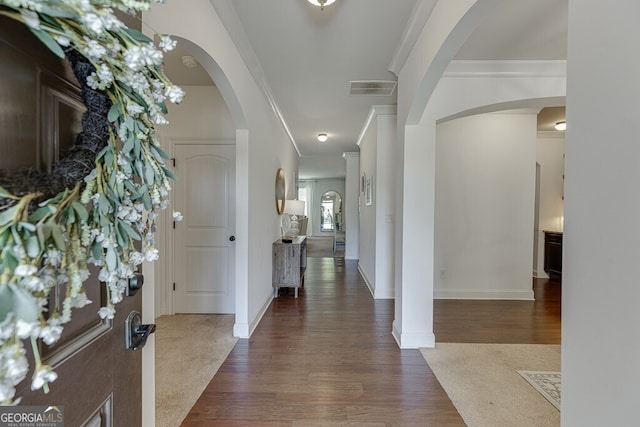 foyer with ornamental molding, dark wood-type flooring, baseboards, and arched walkways