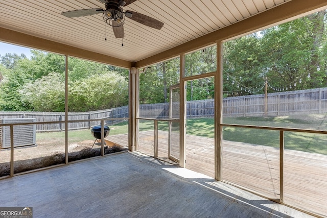 unfurnished sunroom featuring a ceiling fan and view of scattered trees