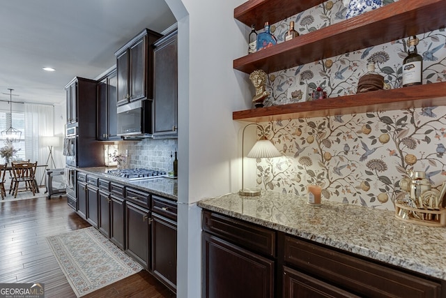 kitchen featuring appliances with stainless steel finishes, open shelves, light stone countertops, tasteful backsplash, and dark wood-style flooring
