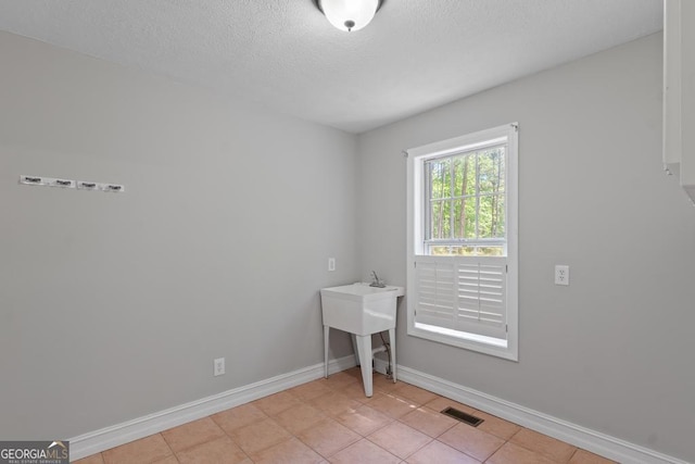 unfurnished room with baseboards, a textured ceiling, and light tile patterned floors