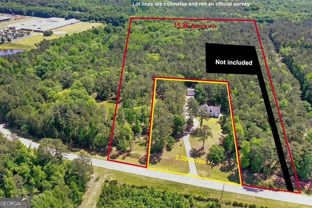 aerial view of property and surrounding area featuring a forest and property parcel outlined