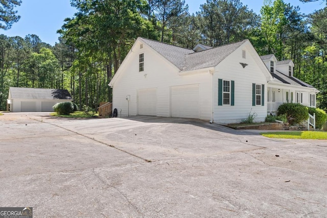 view of home's exterior with driveway and a shingled roof