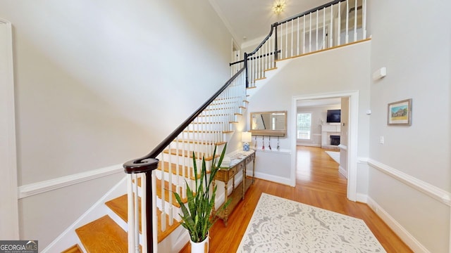 200 N Willow Ct, Alpharetta, GA 30004 - stairway featuring wood finished floors, crown molding, a fireplace with raised hearth, and a towering ceiling