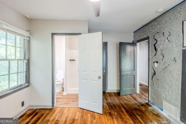 unfurnished bedroom featuring wood finished floors, baseboards, and connected bathroom