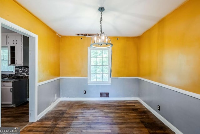 unfurnished dining area featuring dark wood-style flooring and baseboards