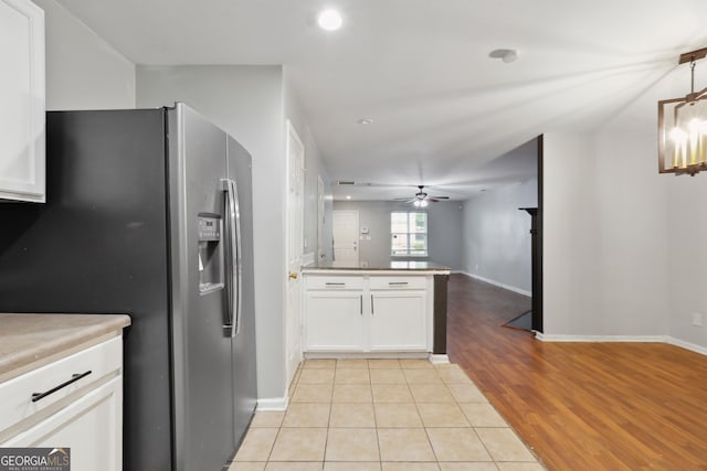 kitchen featuring stainless steel refrigerator with ice dispenser, a peninsula, a ceiling fan, white cabinets, and light wood-style flooring