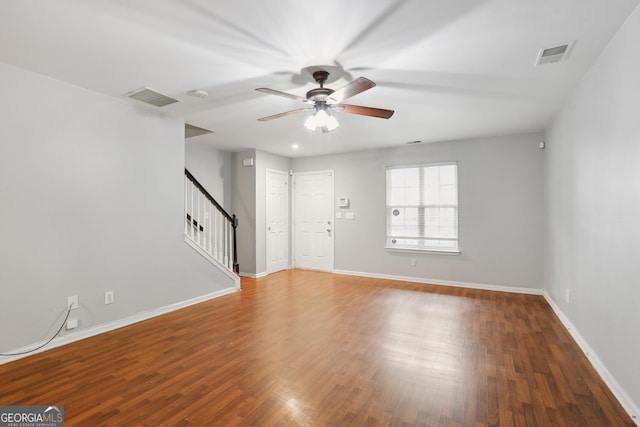 unfurnished living room featuring stairs, a ceiling fan, baseboards, and wood finished floors