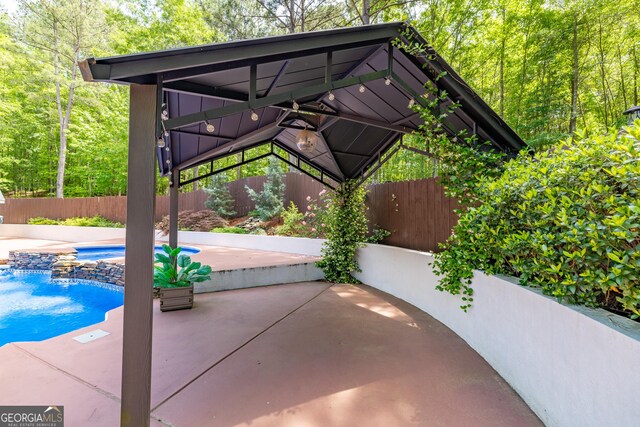 view of patio featuring a gazebo, a fenced backyard, and an in-ground hot tub