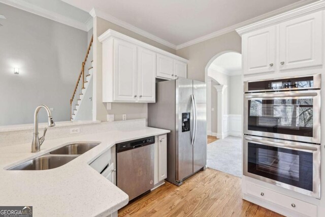 5034 Hickory Hills Dr, Woodstock, GA 30188 - kitchen with appliances with stainless steel finishes, a sink, arched walkways, crown molding, and light wood-style flooring