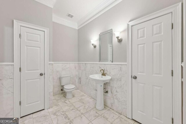 5034 Hickory Hills Dr, Woodstock, GA 30188 - bathroom featuring ornamental molding, wainscoting, toilet, tile walls, and marble look tile flooring