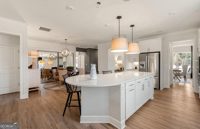 2608 Turnwater St, Hoschton, GA 30548 - kitchen with stainless steel refrigerator with ice dispenser, crown molding, white cabinetry, a center island, and a kitchen bar