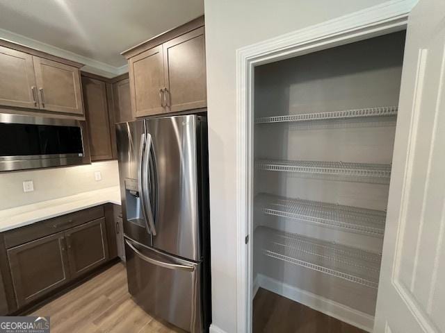 352 Harbour Island Cir, Waverly, GA 31565 - kitchen with stainless steel appliances, light wood finished floors, light countertops, and dark brown cabinetry