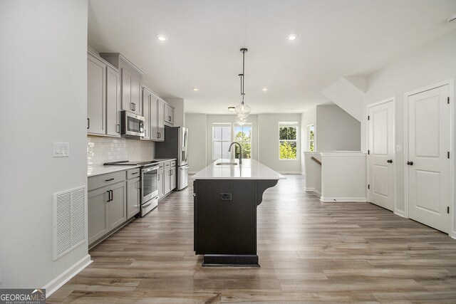 387 Skylar Way SE, Atlanta, GA 30315 - kitchen with stainless steel appliances, a sink, gray cabinets, a center island with sink, and backsplash
