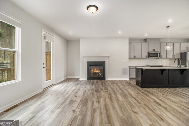 387 Skylar Way SE, Atlanta, GA 30315 - kitchen featuring appliances with stainless steel finishes, a breakfast bar area, light countertops, light wood-style floors, and gray cabinets