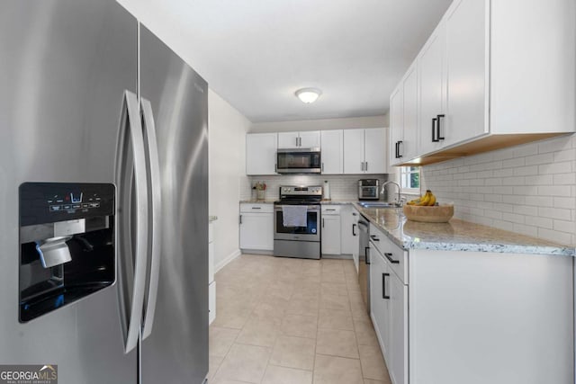 3770 Ponderosa Ln, Powder Springs, GA 30127 - kitchen featuring appliances with stainless steel finishes, a sink, tasteful backsplash, white cabinetry, and light stone countertops