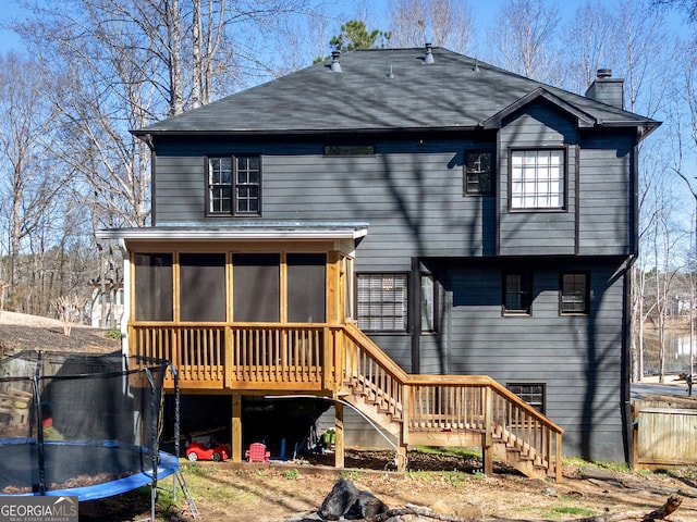 526 Lakeside Dr, Hiram, GA 30141 - back of property featuring a trampoline, stairway, a sunroom, a chimney, and a shingled roof