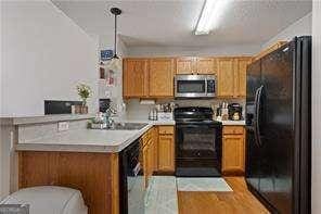210 Cottonwood Creek Cir, Canton, GA 30114 - kitchen with black appliances, a peninsula, light countertops, and brown cabinetry